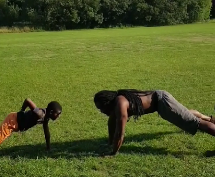 "Father and son bonding in an open field, engaging in push-up exercise routine. Demonstrating the importance of family fitness and quality time spent together."






