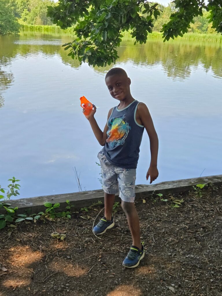 Child playing outdoors by a lake during a home activity that supports speech development for toddlers