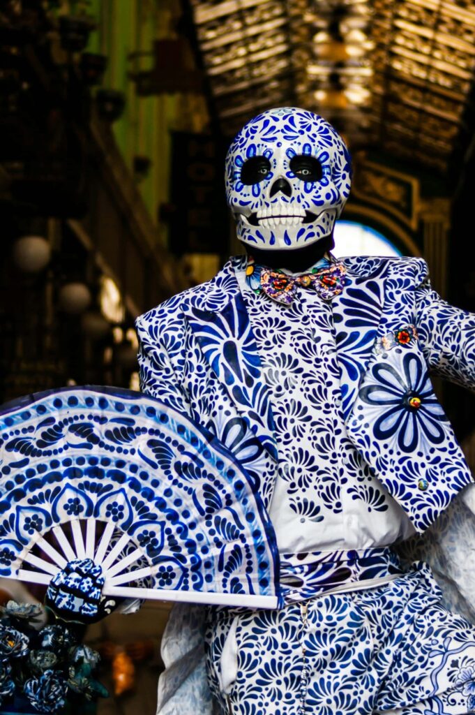 Vibrant Mexican flag waving in the wind, surrounded by iconic symbols like sombreros, mariachi instruments, and Mayan pyramids. A colorful market stall sells traditional crafts while a mariachi band plays in the background
