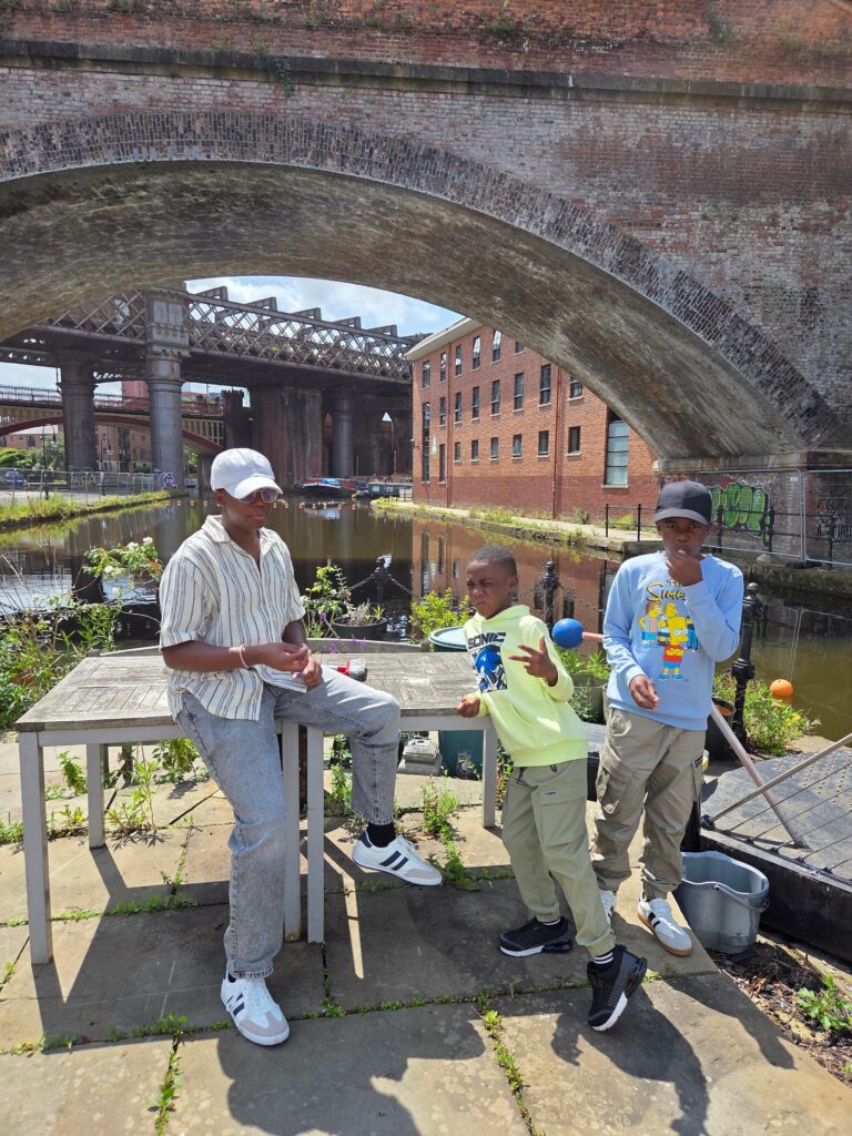 Three boys standing by a canal under a brick bridge, representing a new generation of kids growing up in a different world than their parents.