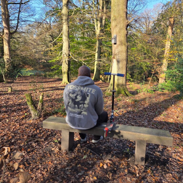 Father sitting alone on a park bench reflecting on the challenges of parenting from afar while staying emotionally connected to his children.