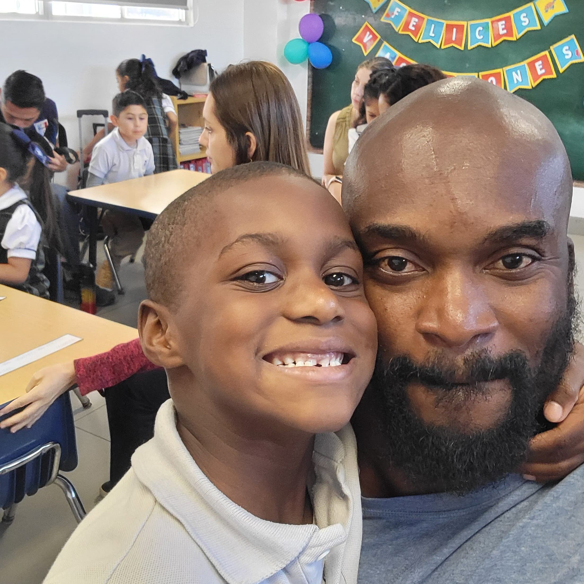Father and son smiling at the camera during at-home speech practice, raising a bilingual child with speech delay